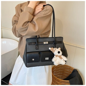 Close-up of contrast tote bag featuring silver twist lock and plush bear charm