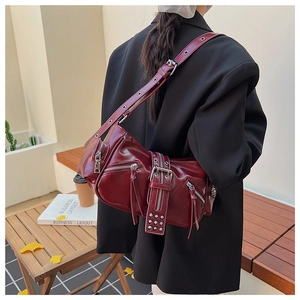 Detail of burgundy leather punk style crossbody bag featuring zippers and buckles