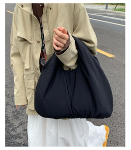Street style view of a large black nylon tote bag with a minimalist slouchy dumpling design