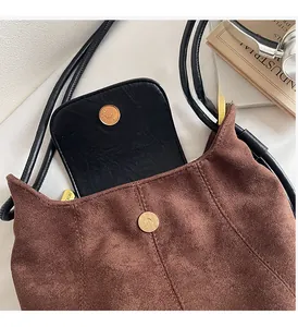 Détail du sac seau en daim marron avec fermoir magnétique doré et rabat en cuir noir