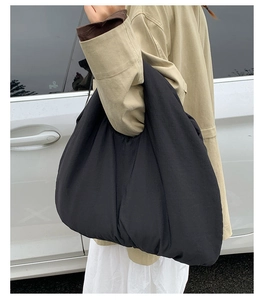 Dettaglio di una borsa tote nera trapuntata portata a spalla in uno stile casual chic