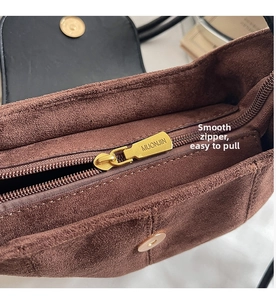 Détail du zip doré et de la boucle métallique sur le sac à bandoulière en daim marron