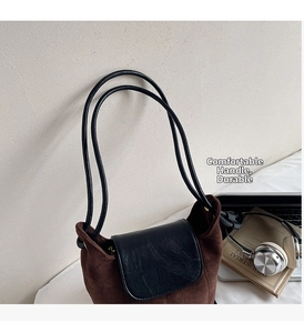 Sac seau marron givré avec rabat en cuir noir sur un bureau avec un ordinateur portable
