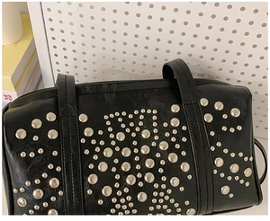 Detail of black leather Boston bag with decorative silver metal studs and punk style texture