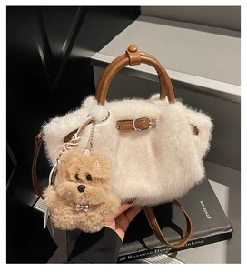 Détail du sac seau en fausse fourrure blanche avec anses en cuir marron et breloque chien