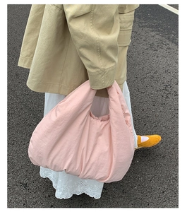 Pink oversized cloud dumpling bag in lightweight fabric shown in an outdoor lifestyle setting