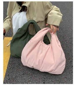 Detailed street view of large capacity puffy tote bags in pink and dark green