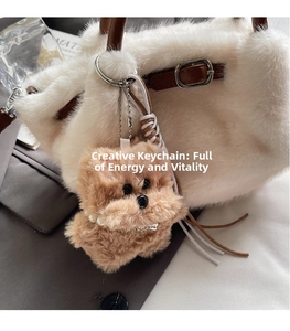 Detailed view of a brown plush dog charm with pearl necklace on a white furry bucket bag