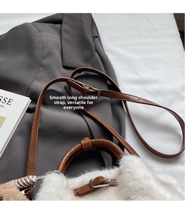 Detail of plush bucket bag with smooth leather strap on grey blazer background