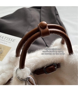 Detail of plush white bucket bag with brown leather handles and silver metal hardware accents