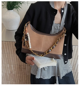 Détail du sac bandoulière vintage en daim marron avec chaîne et breloques en perles