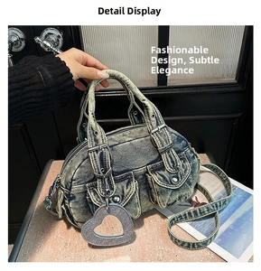 Detail shot of washed denim handbag with utility pockets, metal buckles and heart charm
