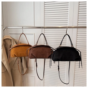 Three minimalist suede baguette bags in tan, brown, and black hanging with fringe detail