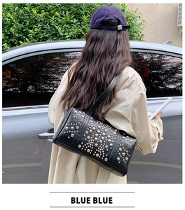Close-up of black cylinder shoulder bag featuring stylish silver studs and leather strap