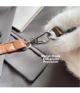 Detail of silver metal lobster clasp and brown leather strap on white plush bucket bag