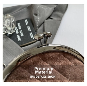 Macro detail of brown quilted suede fabric and polished silver metal frame clasp