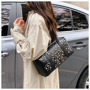 Close-up of black handbag with silver rivet details shown during a street style photoshoot