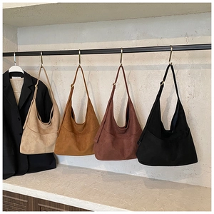 Borse tote in pelle scamosciata in beige, cammello, ruggine e nero appese su un espositore
