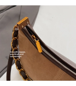 Detailansicht des glatten goldenen Reißverschlusses der braunen Wildledertasche