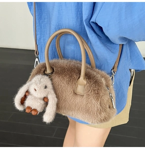 Dettaglio della borsa Boston in ecopelliccia marrone con manici in pelle e charm