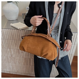 Detail of dark brown suede handbag with embossed logo and detachable shoulder strap