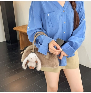 Dettaglio borsa Boston in peluche marrone con manico ad anello e ciondolo coniglietto
