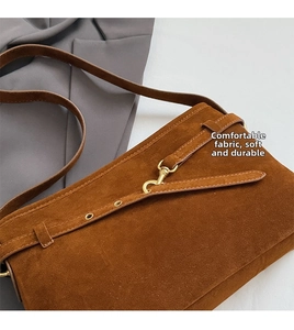 Detailed macro view of the brown suede material and gold metal buckle on this retro shoulder bag