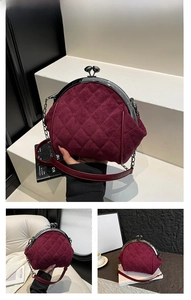 Detail of wine red quilted suede handbag with kiss-lock clasp and metal chain strap