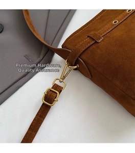 Detailed close-up of premium brown suede bag with gold buckle and adjustable strap