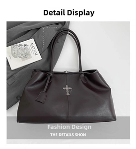 Dettaglio della borsa tote marrone scuro con ciondolo a croce vintage e targhetta in pelle