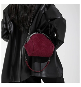 Detail of burgundy quilted suede shell bag with vintage silver metal clasp and chain strap
