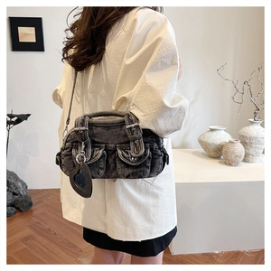 Detail of grey washed denim shoulder bag with multiple flap pockets and heart charm