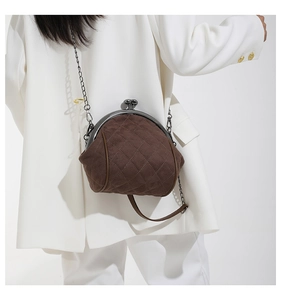 Close-up of vintage dark brown suede frame bag with quilted stitching and metal chain