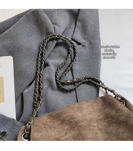 Detail der braunen Wildleder-Tragetasche mit einem hochwertigen Kettenriemen aus Leder und Metall