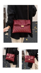 Detail view of quilted burgundy chain bag with golden square turn-lock closure