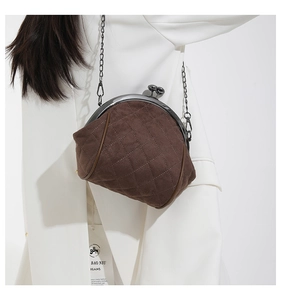 Detail of dark brown quilted suede shell bag with metal chain strap and kiss-lock clasp