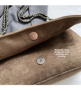 Detail der braunen Wildledertasche mit Magnetverschluss und Metallketten-Schultergurt