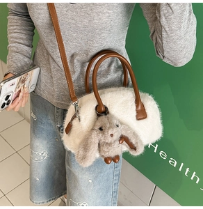 Detailed view of white faux fur handbag with brown handles and cute grey rabbit pendant