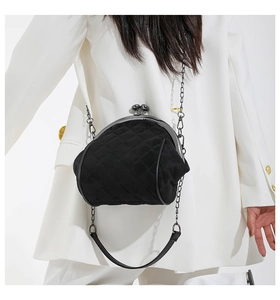 Detail of vintage black quilted crossbody bag featuring ball clasp and metal chain strap