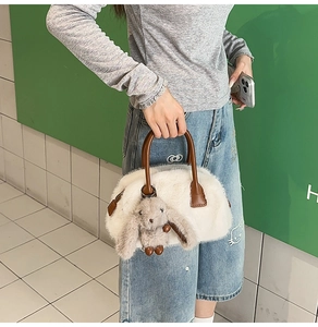 Dettaglio della borsa bowling in peluche con manici in pelle marrone e ciondolo a coniglio