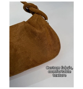 Detailed macro shot of caramel brown suede handbag featuring custom textured fabric