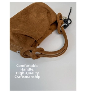 Detail of the brown suede bucket bag featuring a thick knotted handle and silver hardware