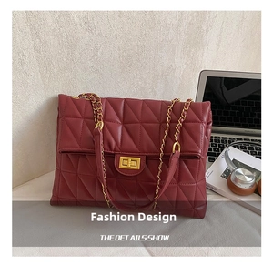 Detail of burgundy quilted shoulder bag with gold twist lock and chain strap