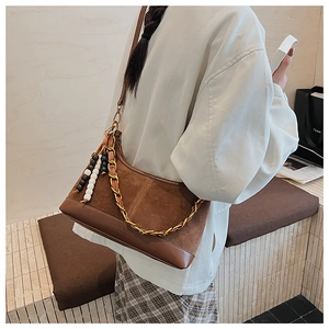 Vue détaillée du sac en daim marron avec chaîne dorée et pompon à franges perlées
