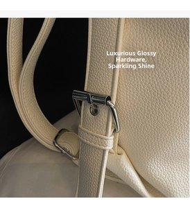 Detail of adjustable strap with silver buckle on beige litchi grain leather tote bag