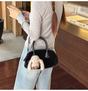 Dettaglio borsa nera in peluche con ciondolo a coniglio e tracolla sottile