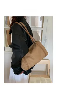 Detailed view of camel suede pillow tote bag with leather strap on model shoulder