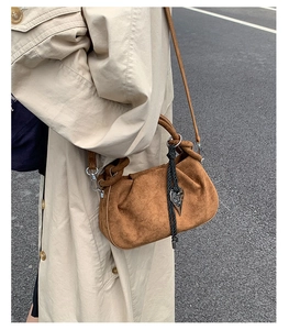 Detail of dark brown pleated suede bag with heart charm and woven rope decoration