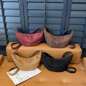 Chic suede crescent bags in burgundy, brown, khaki, and black on a bench