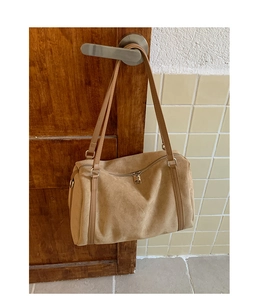 Détail d'un sac bandoulière en daim kaki montrant la texture douce et le zip métallique